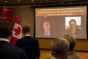 A video screen displays images of Canadians Michael Kovrig, left, and Michael Spavor at an event held in connection with the announcement of the sentence for Spavor at the Canadian Embassy in Beijing, Wednesday, Aug. 11, 2021. A Chinese court has sentenced Spavor to 11 years on spying charges in case linked to Huawei. (AP Photo/Mark Schiefelbein)