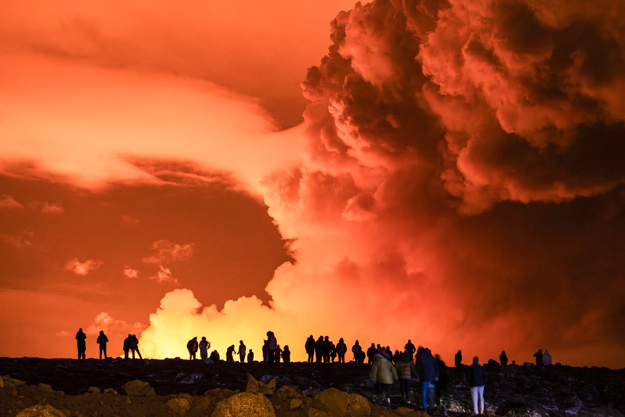 La gente se reúne para observar cómo la lava fundida fluye desde una fisura en la península de Reykjanes, al norte de la ciudad evacuada de Grindavik, en el oeste de Islandia, el 16 de marzo de 2024.