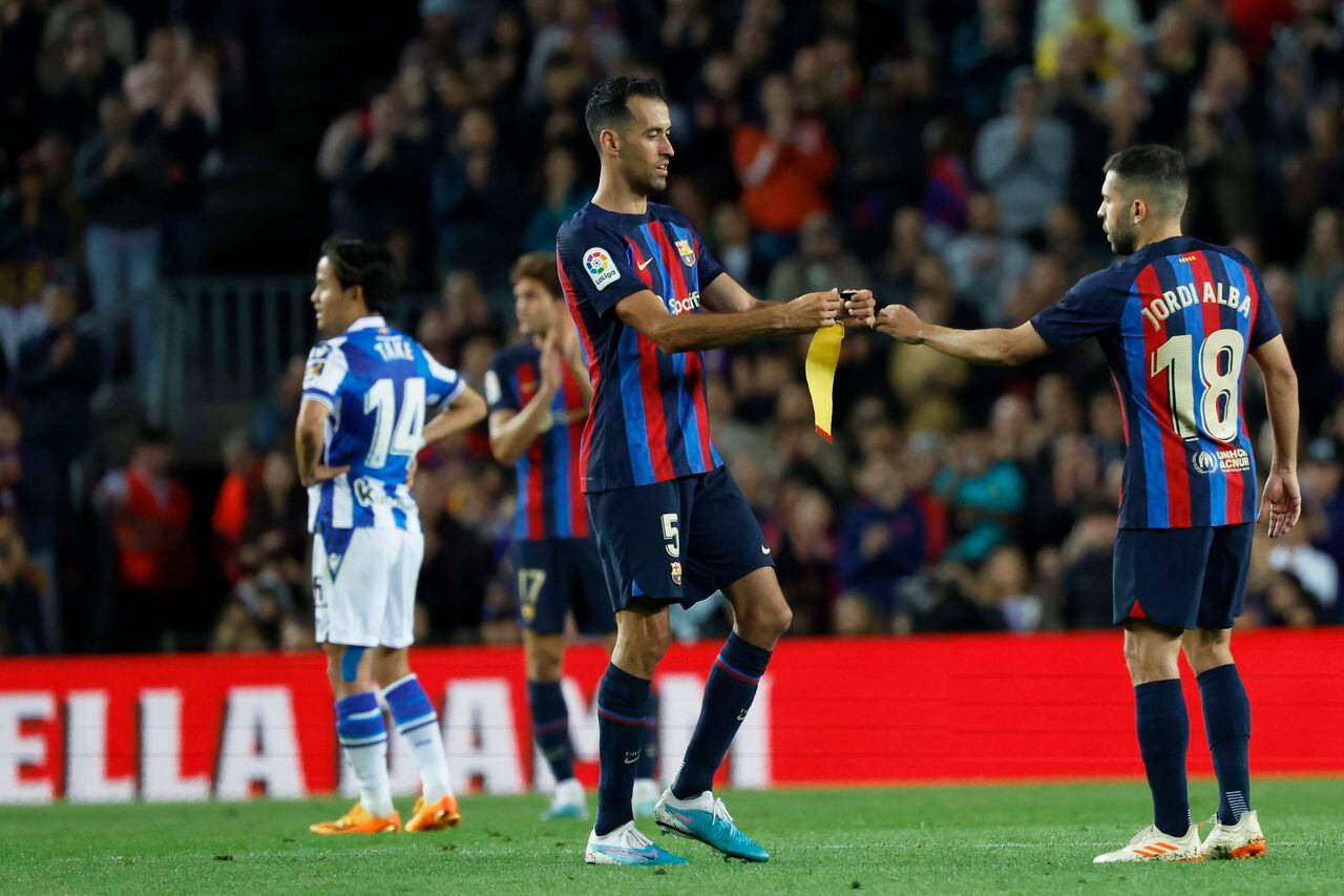 Barcelona's Sergio Busquets gives the captain armband to teammate Jordi Alba, right, before leaving the pitch to be replaced during a Spanish La Liga soccer match between Barcelona and Real Sociedad at Camp Nou stadium in Barcelona, Spain, Saturday, May 20, 2023. (AP Photo/Joan Monfort)