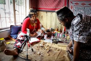 Traditional healer Gogo Kamo (L), does an online consultation with a client in her consultation room in Kempton Park, South Africa on April 16, 2021. - Known as "sangomas" in Zulu language, traditional healers are qualified herbalists, councillors and community mediators as well as diviners.   
Many South Africans consult healers for various illness, dream interpretations and conflict resolution.
Shrouded in misconception, sangomas were banned in 1957 under the "Witchcraft Suppression Act" and only legally recognised decades later as "traditional health practitioners".
The passing of knowledge skipped a generation as a result, with grand-parents training millenial grand-children more inclined to break with tradition.
Many traditional healers had to digitalise an ancient practice to continue offering consultations amid strict coronavirus restrictions last year.
The shift has spurred a budding pre-pandemic trend of younger traditional healers already engaging clients through social media and video calls. (Photo by Guillem Sartorio / AFP)