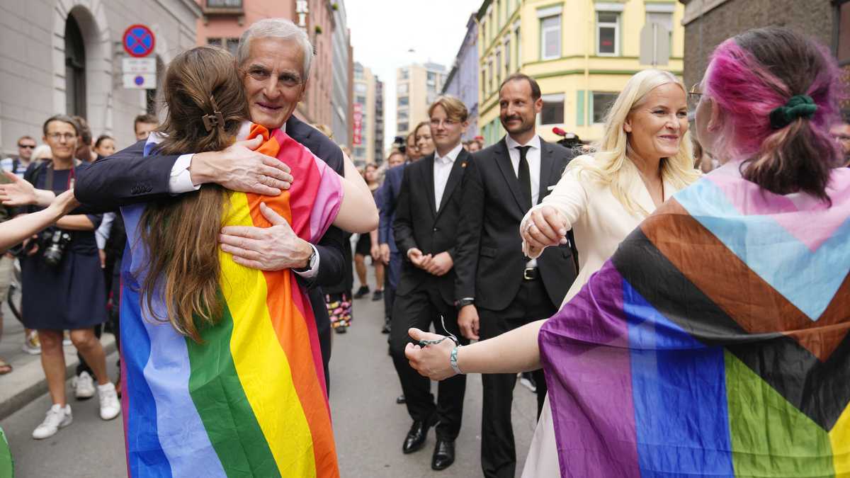 El primer ministro noruego Jonas Gahr Store y la princesa heredera Mette-Marit de Noruega abrazan a las personas con un arcoíris y una bandera de progreso mientras visitan la escena del crimen el 25 de junio de 2022, luego de un tiroteo afuera de pubs y clubes nocturnos en el centro de Oslo que mató a dos personas. hiriendo 21. (Foto de Javad Parsa / NTB / AFP) / Noruega FUERA