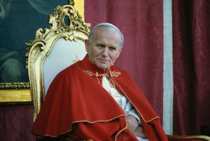 11/2/1982- Avila, Spain: Close-up of Pope John Paul II sitting on a chair, wearing red robes with a portrait of the St. Theresa of Avila in the background during his visit to Avila, Spain.