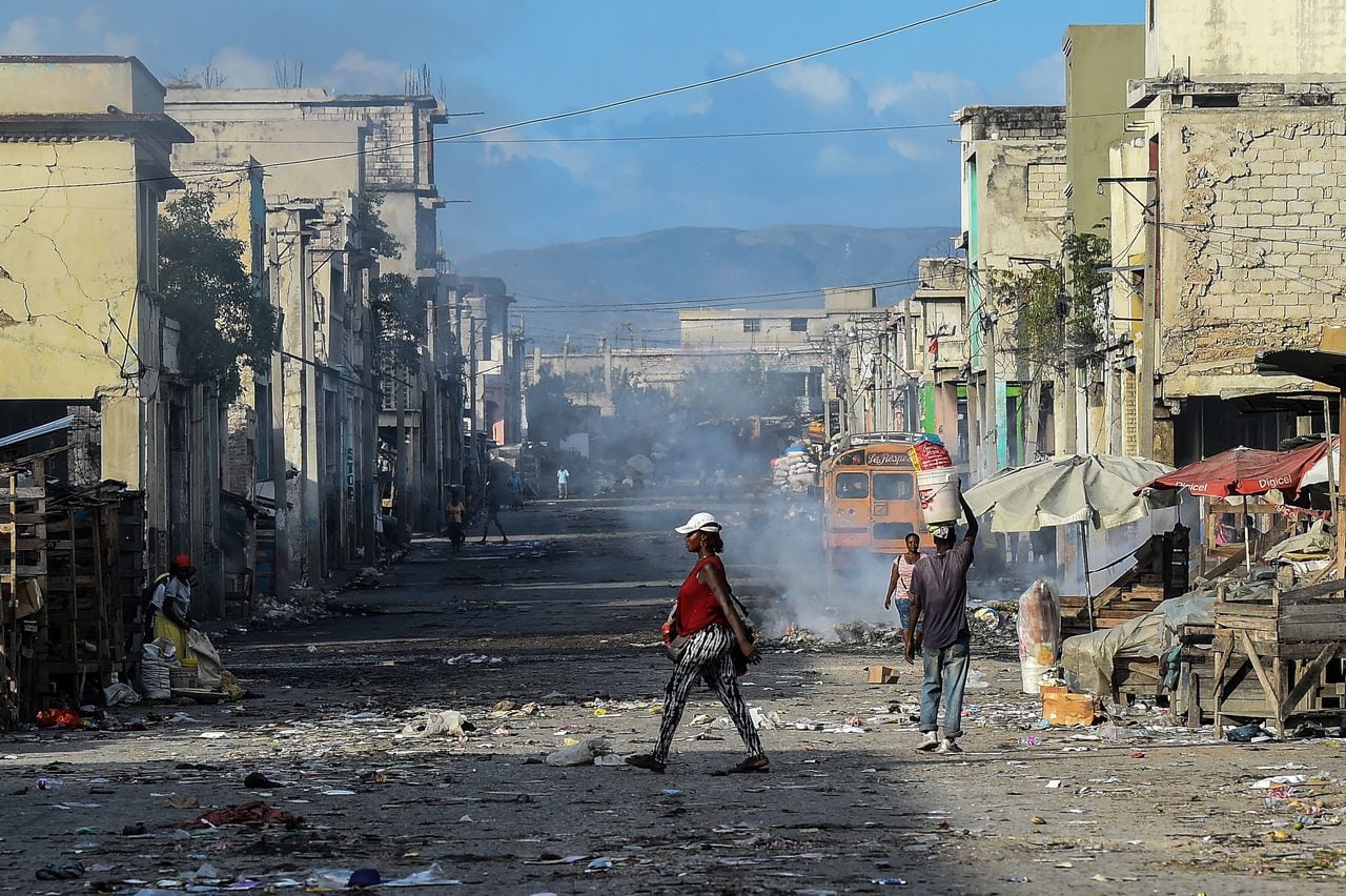 (FILES) In this file photo taken on December 20, 2019, eople walk on the deserted road ahead of gang shootings in downtown in Port-au-Prince. - Long confined to the slums, the gangs have gradually extended their control in Haiti and the nearly three million inhabitants of Port-au-Prince are forced to adapt their daily lives to this reality, for fear of being the next victim. "The gangs today reign supreme and lords over the country," laments G�d�on Jean, director of the Center for Analysis and Research in Human Rights, based in the Haitian capital. (Photo by CHANDAN KHANNA / AFP)