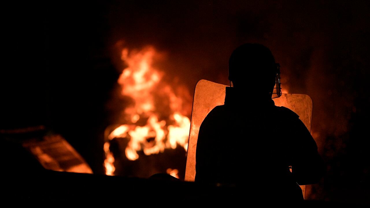 A riot police officer stands in front of a bonfire during a protest against police brutality in Bogota, on September 10, 2020. - At least 10 people were killed and hundreds wounded after rioting broke out in the Colombian capital Bogota during protests over the death of a man repeatedly tasered by police, authorities said Thursday. (Photo by Raul ARBOLEDA / AFP)