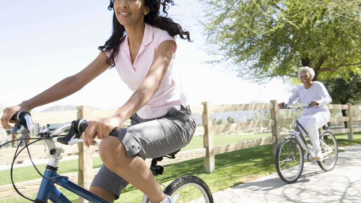 madre e hija haciendo ejercicio en bicicleta, aire libre, salud.
