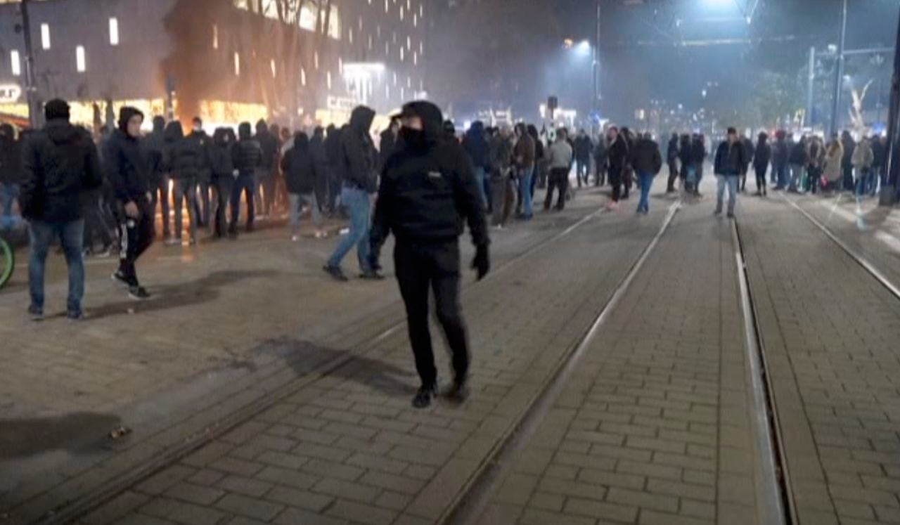 Esta imagen tomada de un video muestra a manifestantes protestando contra las restricciones ordenadas por el gobierno para controlar la pandemia del coronavirus, el viernes 19 de noviembre de 2021, en Rotterdam, Holanda. (Media TV Rotterdam vía AP)