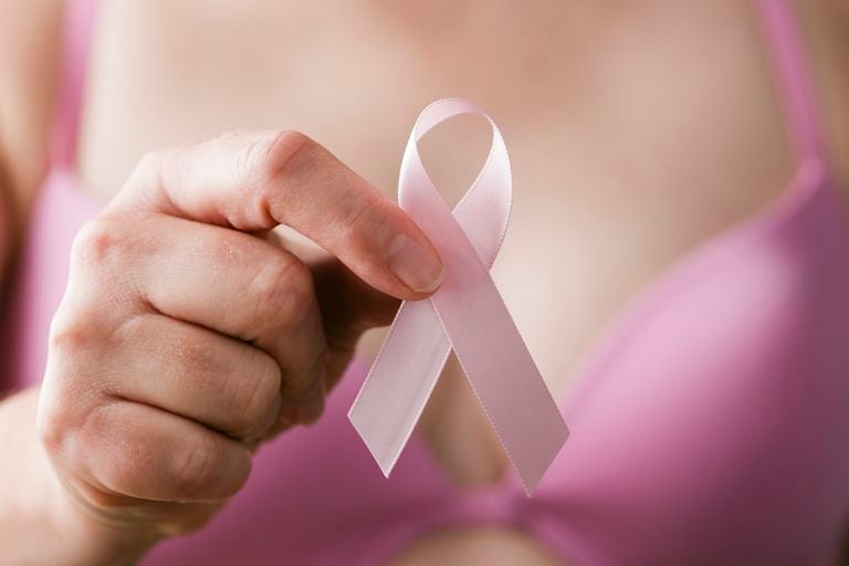 Mujer en sujetador rosa sosteniendo una cinta rosa, un recordatorio de la importancia del examen de mama en la atención médica para mantener y mantener un estilo de vida saludable y libre de cáncer