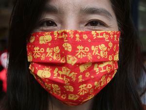 Una mujer usa una máscara china con un patrón de caracteres auspiciosos con "Kung Hei Fat Choi, Hong Bao Na Lai (Le deseo una fortuna, tráigame el sobre rojo)" para ayudar a frenar la propagación del coronavirus durante el Año Nuevo Lunar chino en Taipei, Taiwán, viernes 12 de febrero de 2021. Foto: AP / Chiang Ying-ying.