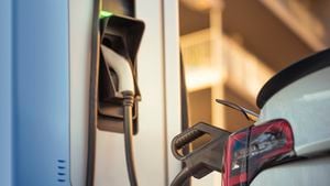 Coche eléctrico blanco cargando la batería en la estación de carga en la calle, concepto de energía alternativa