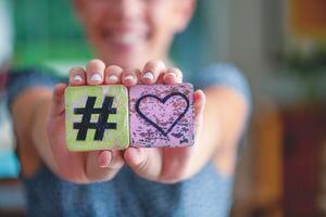 Mujer sosteniendo un signo de corazón de amor hashtag y sonriendo. Concepto de agrado de influencer en línea.