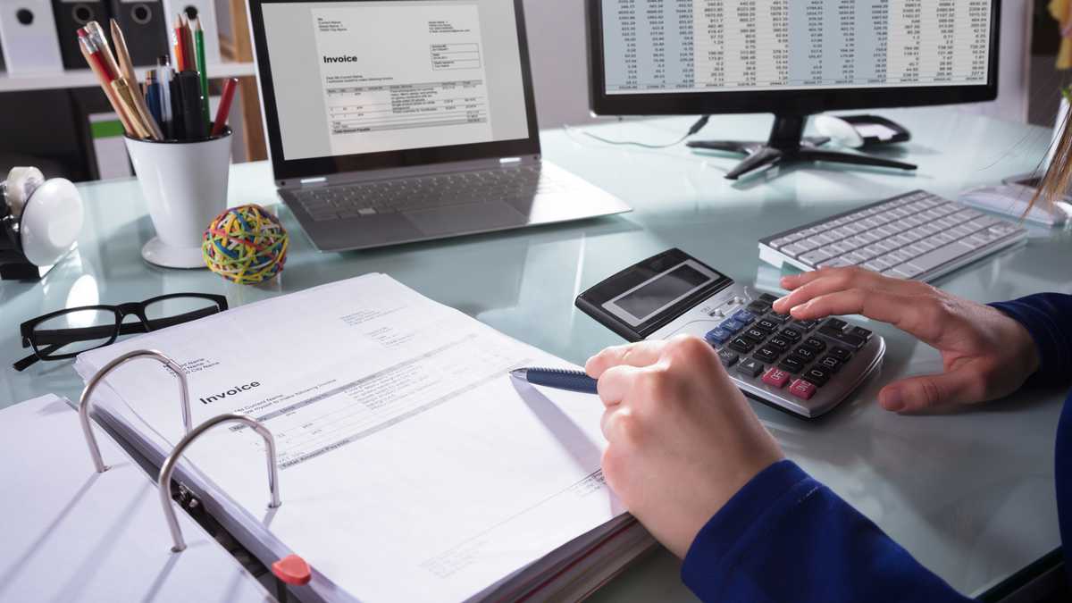 Close-up de la mano de un empresario calcular la factura en el lugar de trabajo