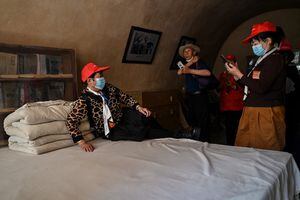 Esta foto tomada durante un tour de medios organizado por el gobierno muestra a un turista posando en una cama para una foto en la antigua residencia del ex líder chino Mao Zedong en el Sitio Revolucionario Yangjialing en Yan'an, la sede del Partido Comunista Chino desde 1936 hasta 1947, en la provincia de Shaanxi el 10 de mayo de 2021, antes del centenario de la fundación del partido en julio. Foto de Hector RETAMAL / AFP