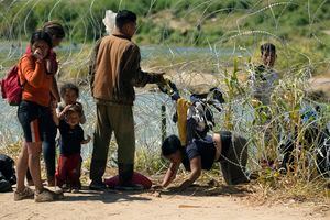 Migrantes que cruzaron a Estados Unidos desde México pasan por debajo de un alambre con cuchillas en al frontera del Río Bravo, el 21 de septiembre de 2023, en Eagle Pass, Texas. (AP Foto/Eric Gay)