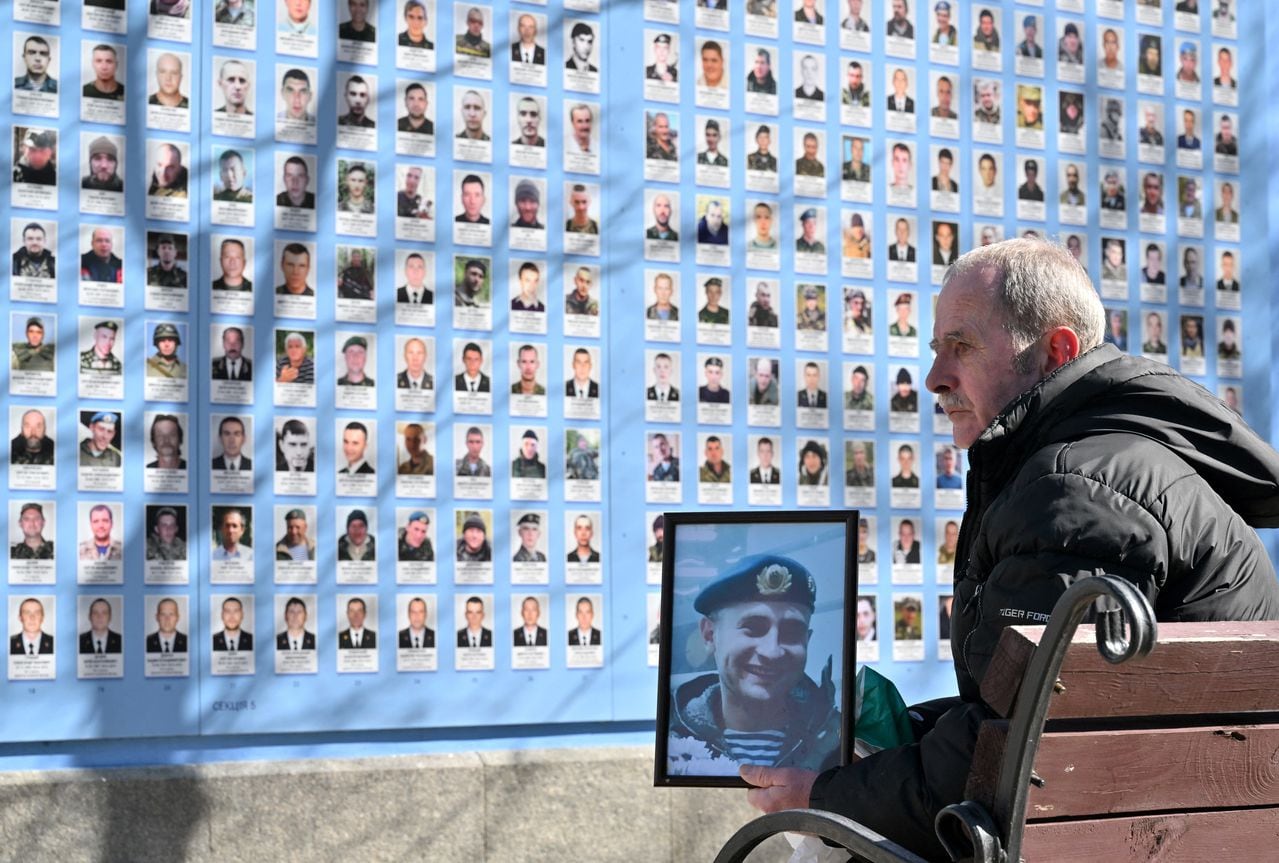 Un hombre sostiene una foto de su hijo en el Muro de la Memoria de los defensores caídos de Ucrania en la guerra ruso-ucraniana durante una ceremonia que marca el Día del Voluntariado en Kiev el 14 de marzo de 2023. (Foto de Sergei SUPINSKY / AFP)