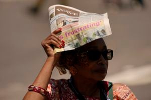 Una mujer se protege de la luz del sol con una copia del periódico Los Angeles Wave durante el "#BLM Turns 10 People's Justice Festival" el sábado 15 de julio de 2023 en el vecindario de Leimert Park en Los Ángeles