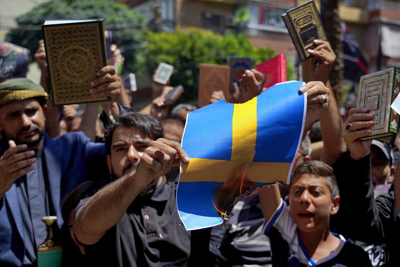 Partidarios de Hezbolá cantan eslóganes mientras queman representaciones de la bandera sueca durante una manifestación que denuncia la profanación del Corán después de las oraciones del viernes en el suburbio de Dahiyeh, en el sur de Beirut, Líbano, el viernes 21 de julio de 2023.
