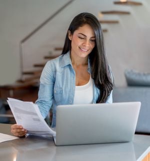 Mujer latinoamericana pagando facturas en línea en casa usando una computadora portátil - conceptos de tecnología. Recibos.