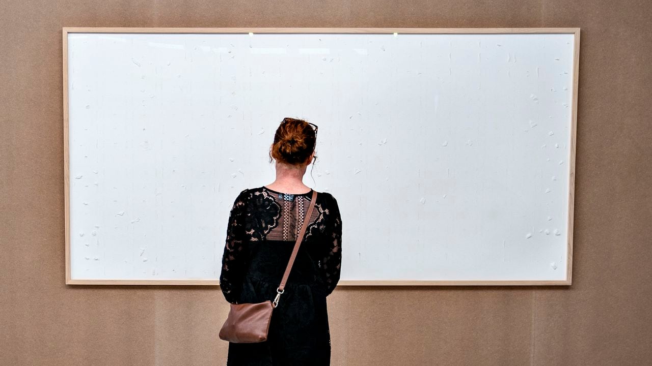 Una mujer admira el marco vacío de la obra "Toma el dinero y lárgate" de Jens Haaning, en el Kunsten Museum. Aalborg, Dinamarca, 28 de septiembre de 2021. Foto: Henning Bagger / Ritzau Scanpix / AFP