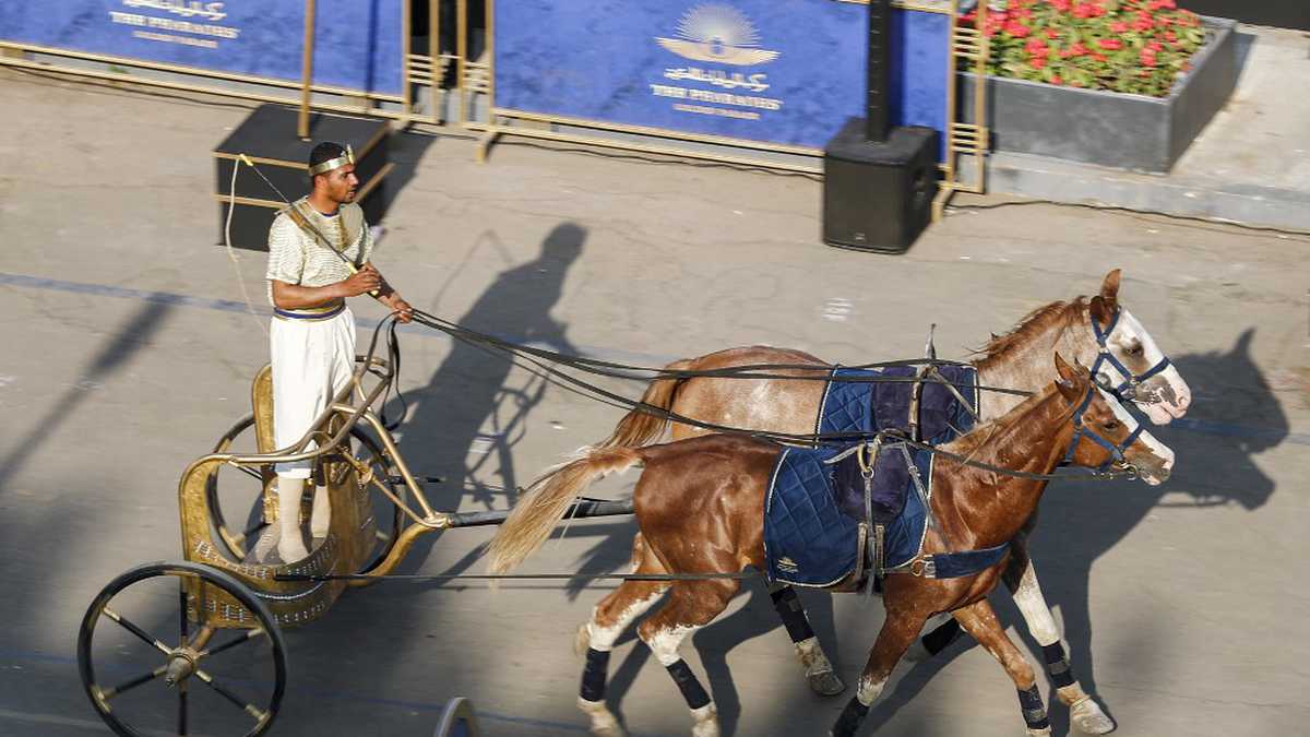 Un actor disfrazado monta un carro de dos caballos en la plaza Tahrir, en el centro de El Cairo. El 3 de abril de 2021 se realizó un un ensayo del desfile de 22 momias reales del antiguo Egipto que partirá del Museo Egipcio de Tahrir hacia su nuevo lugar de descanso en el nuevo Museo Nacional de la Civilización Egipcia (NMEC), a unos siete kilómetros al sur, en el histórico Fustat (El Cairo antiguo). - Bautizado como el Desfile Dorado de los Faraones, los 18 reyes y las cuatro reinas viajarán en orden, los más antiguos primero, cada uno a bordo de una carroza independiente decorada al estilo del antiguo Egipto. Foto de Khaled DESOUKI / AFP.