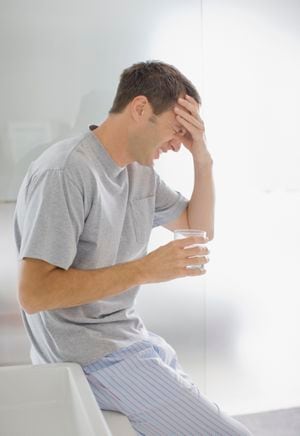 Hombre con dolor de cabeza bebiendo agua