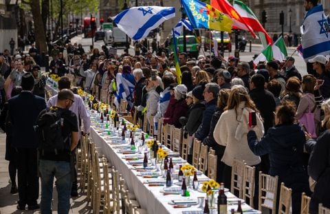 La gente se reúne alrededor de una mesa del Seder vacía con 133 sillas que representan a los rehenes tomados por Hamas el 7 de octubre, durante una protesta frente a Downing Street el 17 de abril de 2024 en Londres, Inglaterra.