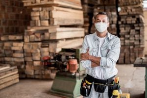 Feliz carpintero latinoamericano que trabaja en su taller con una mascarilla para evitar el coronavirus - “conceptos de estilo de vida pandémico