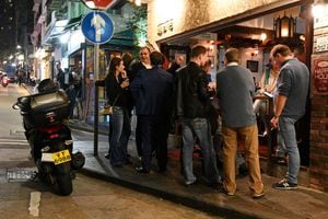 La gente se reúne frente a un bar en Hong Kong el 6 de enero de 2022, antes del cierre del 7 de enero de gimnasios, bares y cenas en restaurantes por la noche tras el anuncio de nuevos controles estrictos contra el coronavirus después de que se detectara la variante Omicron. (Foto de Peter PARKS / AFP)