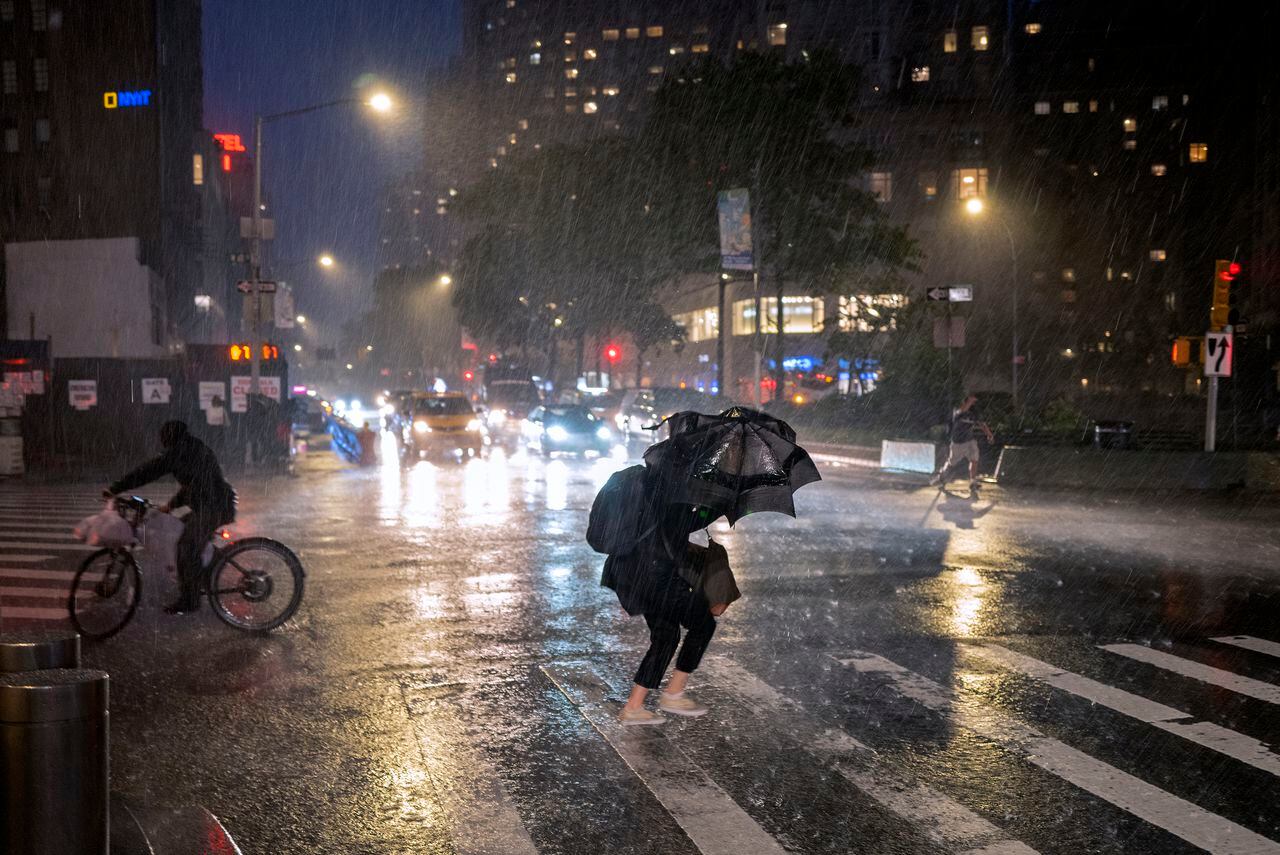 Peatones cubriéndose en la calle cerca de Columbus Circle, en la ciudad de Nueva York, el miércoles 1 de septiembre de 2021, al paso de los restos del huracán Ida. (AP Fhoto/Craig Ruttle)