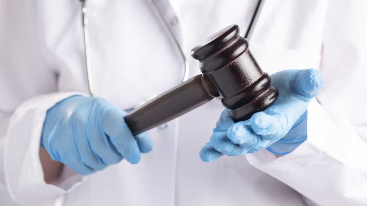 Doktor's hands with blue glove are hanging a gavel.
