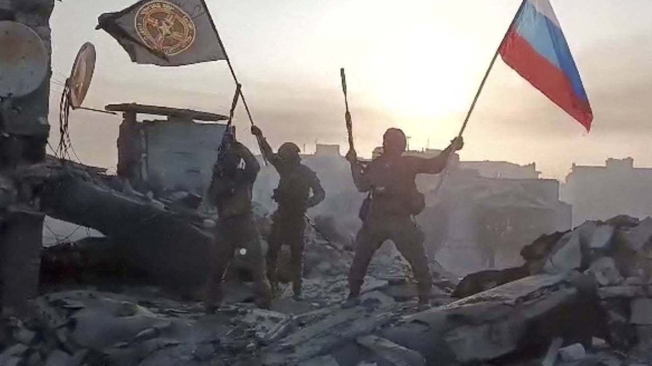 Los combatientes del grupo mercenario Wagner ondean banderas de Rusia y el grupo Wagner en lo alto de un edificio en un lugar no identificado. imagen obtenida de un video publicado el 20 de mayo de 2023.