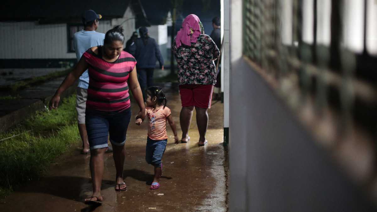 Una mujer y su hija caminan en un refugio temporal antes de la llegada de la tormenta tropical Bonnie en Bluefields, Nicaragua, el 1 de julio de 2022.