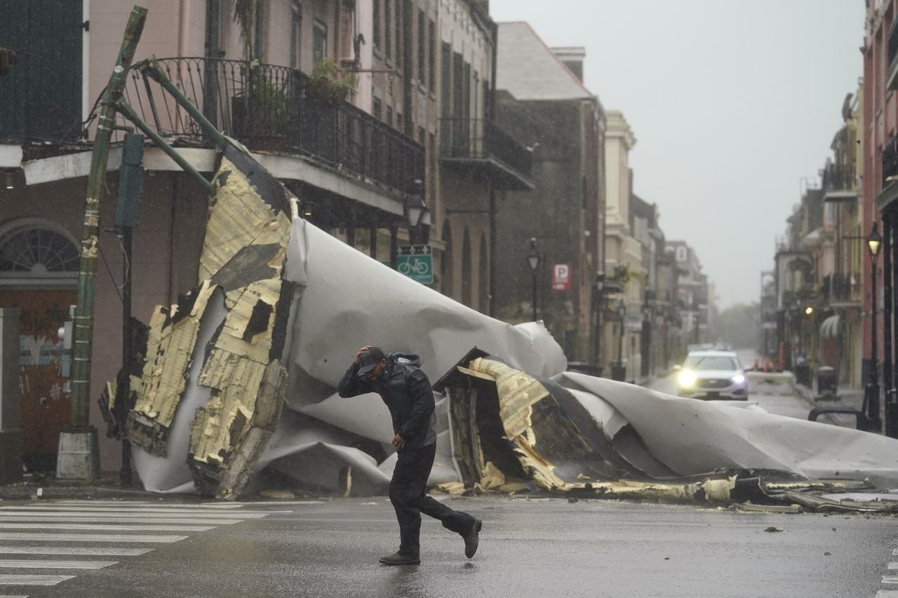 Un hombre camina frente a la parte de un techo que fue arrancado de un edificio por los vientos del huracán Ida, el domingo 29 de agosto de 2021, en Nueva Orleans. (AP Foto/Eric Gay)