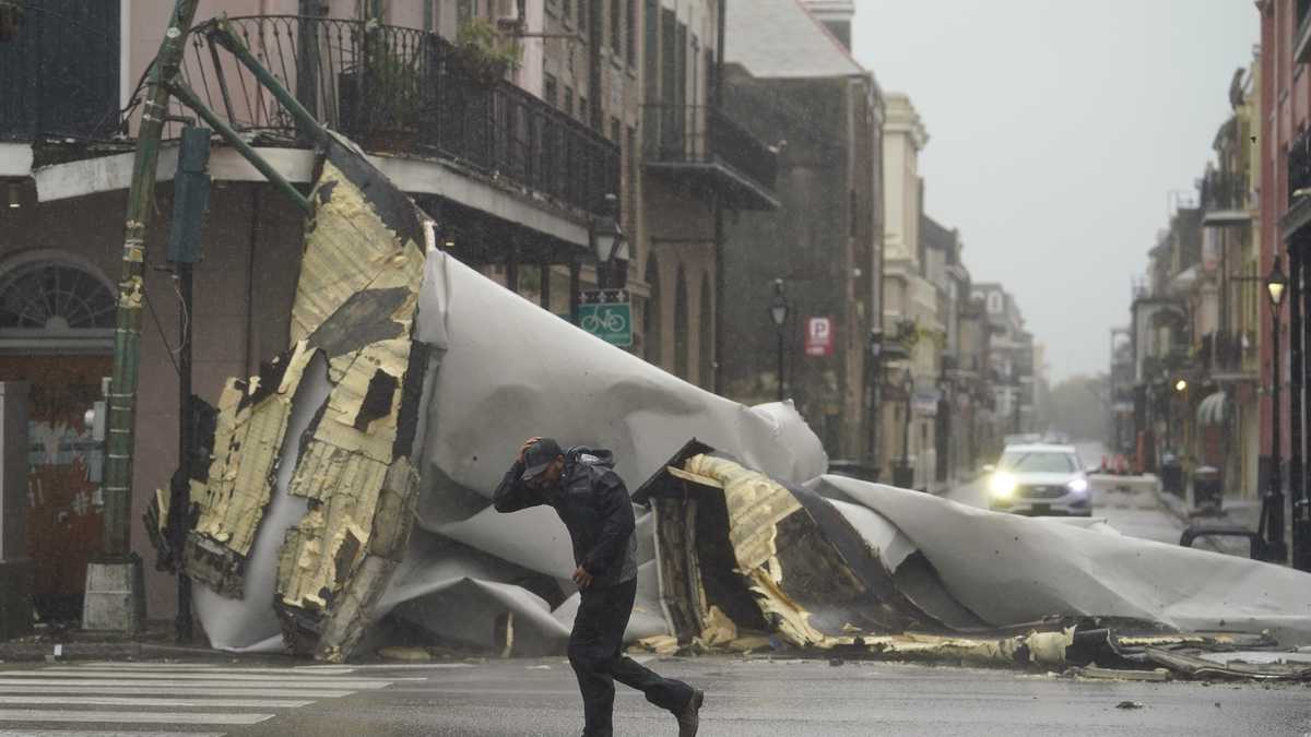 Un hombre camina frente a la parte de un techo que fue arrancado de un edificio por los vientos del huracán Ida, el domingo 29 de agosto de 2021, en Nueva Orleans. (AP Foto/Eric Gay)
