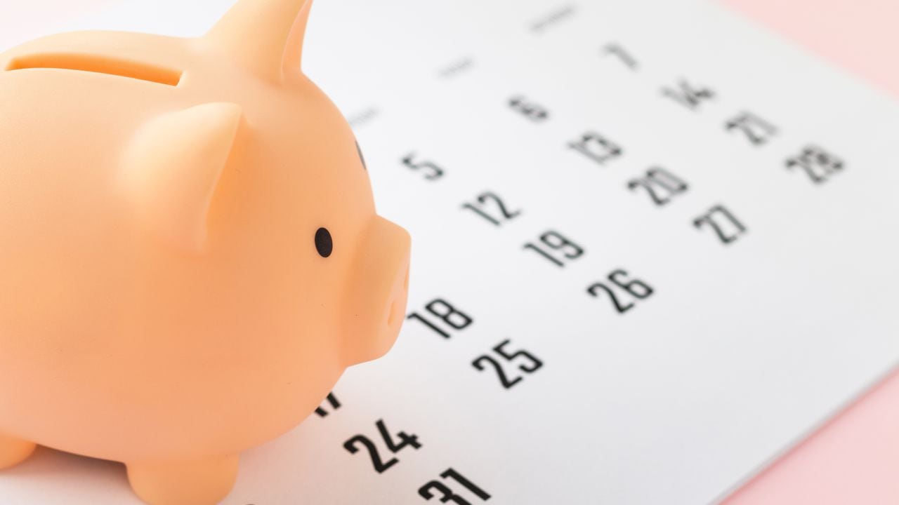 Money pig and calendar on pink background. Deadline, business, finance concept.