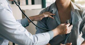 Asian doctor is using a stethoscope listen to the heartbeat of the elderly patient.