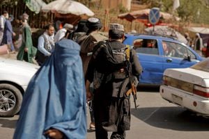 Miembros de las fuerzas talibanes patrullan mientras una mujer vestida con burka camina en una calle en Kabul. Foto REUTERS / Jorge Silva