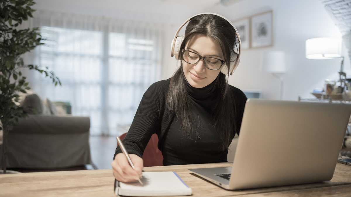 Mujer joven con ordenador portátil en casa. Mujer trabajando desde casa en su computador portatil.