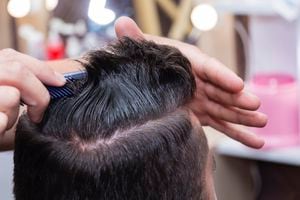 Peinado y cuidado del cabello para hombres con la ayuda de una máquina de tijeras y corte de cabello en la peluquería.