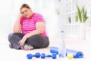 Mujer con sobrepeso deprimida sentada en el suelo y no quiere hacer ejercicio.