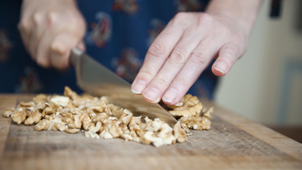 Woman using a big knife to chop walnuts