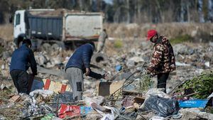La gente busca billetes de dólar entre la basura, en el basurero de Las Parejas, provincia de Santa Fe, Argentina, el 20 de julio de 2022. STR / AFP