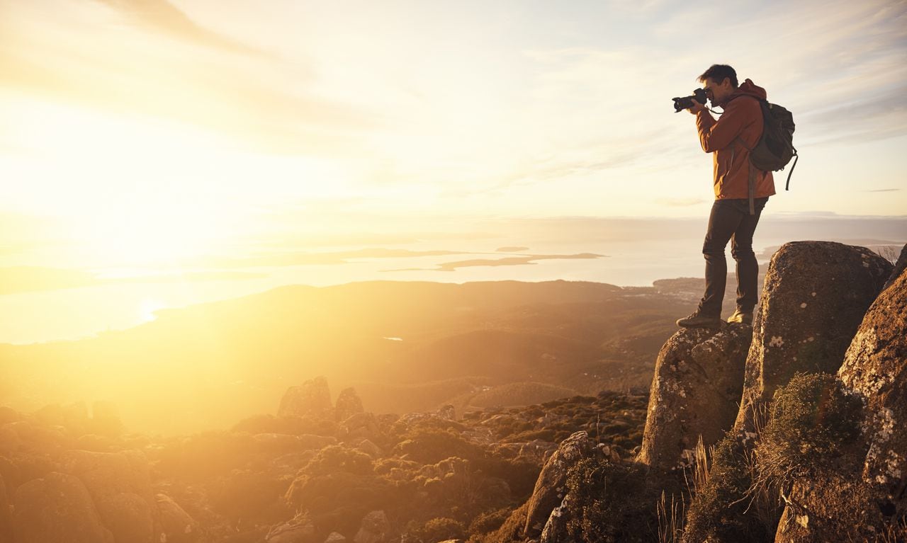 Foto de un joven tomando fotografías desde la cima de una montaña