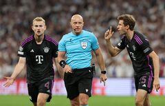 El árbitro Szymon Marciniak observa a Matthijs de Ligt y Thomas Mueller del Bayern München durante el partido de vuelta de semifinales de la UEFA Champions League entre el Real Madrid y el FC Bayern München en el Estadio Santiago Bernabeu el 08 de mayo de 2024 en Madrid, España.