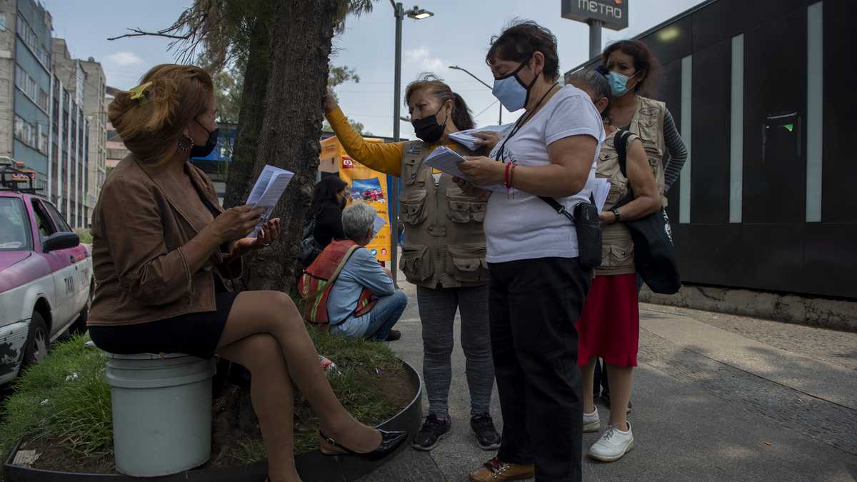 Members of the NGO Elisa Mart�nez Street Brigade in Support of Woman, give a copy of the newspaper �Noticalle� to a sex worker in Mexico City, on June 30, 2022. - Women -mostly sex workers- write for a free monthly magazine called Noticalle published by the non-governmental organization Brigada Callejera (Street Brigade) to decry injustices. (Photo by CLAUDIO CRUZ / AFP)
