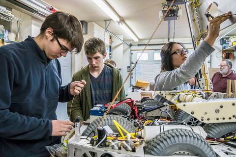 Robotics students adjusting machinery