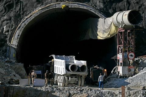 El personal de seguridad observa cómo un camión transporta tubos metálicos a través de una entrada del túnel de carretera en construcción de Silkyara, días después de que colapsara en el distrito de Uttarkashi del estado indio de Uttarakhand el 21 de noviembre de 2023.