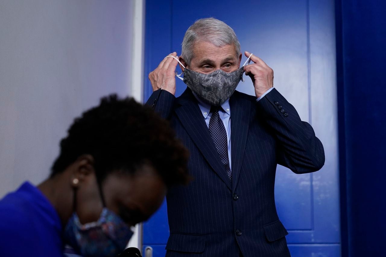 Dr. Anthony Fauci, director of the National Institute of Allergy and Infectious Diseases, puts his face mask back on after speaking with reporters in the James Brady Press Briefing Room at the White House, Thursday, Jan. 21, 2021, in Washington. (AP Photo/Alex Brandon)