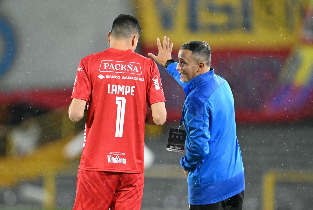 Bolivar's Argentine coach Flavio Robatto (R) speaks with Bolivar's goalkeeper Carlos Lampe fight for the ball during the Copa Libertadores group stage second leg football match between Colombia's Millonarios and Bolivia's Bolivar at the Nemesio Camacho "El Campin" stadium in Bogota on May 8, 2024. (Photo by RAUL ARBOLEDA / AFP)