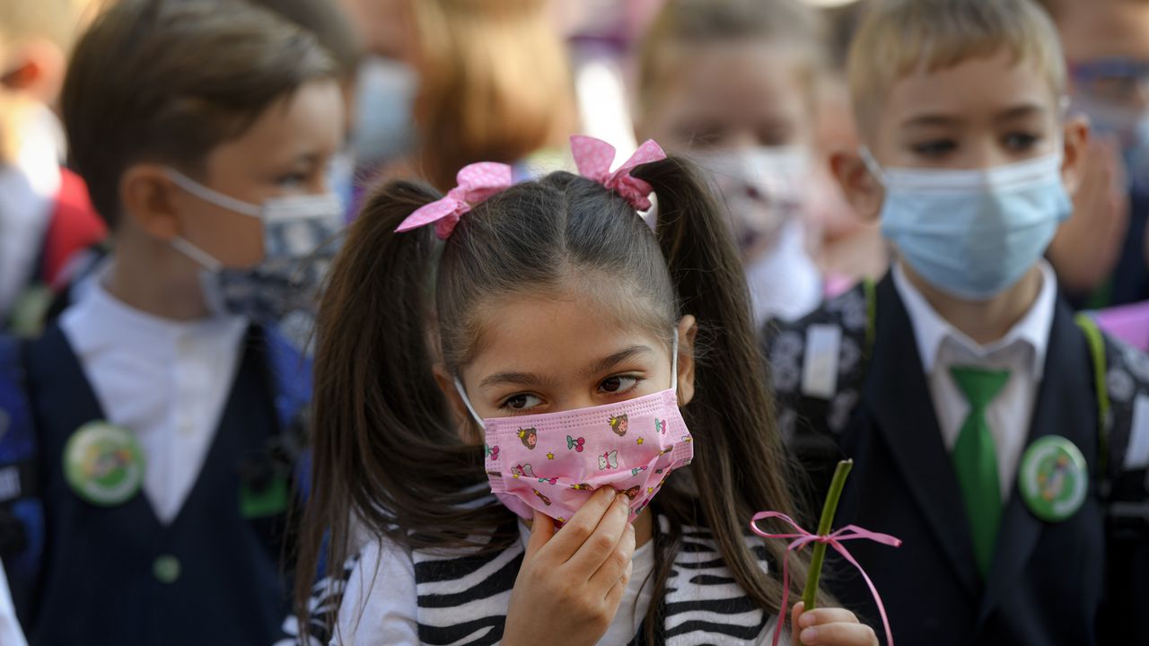 Una niña se acomoda la mascarilla durante las festividades que marcan el comienzo del año escolar. (Foto AP / Andreea Alexandru)