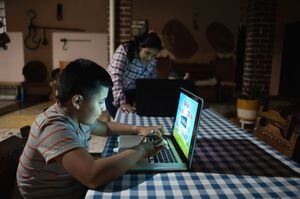 Niños latinoamericanos que estudian en casa usando computadoras portátiles con la supervisión de su madre: conceptos educativos. **LA IMAGEN EN LA PANTALLA FUE HECHA DESDE CERO POR NOSOTROS**